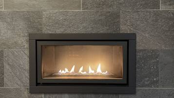 A modern fireplace with a stone wall backdrop and a dark frame.