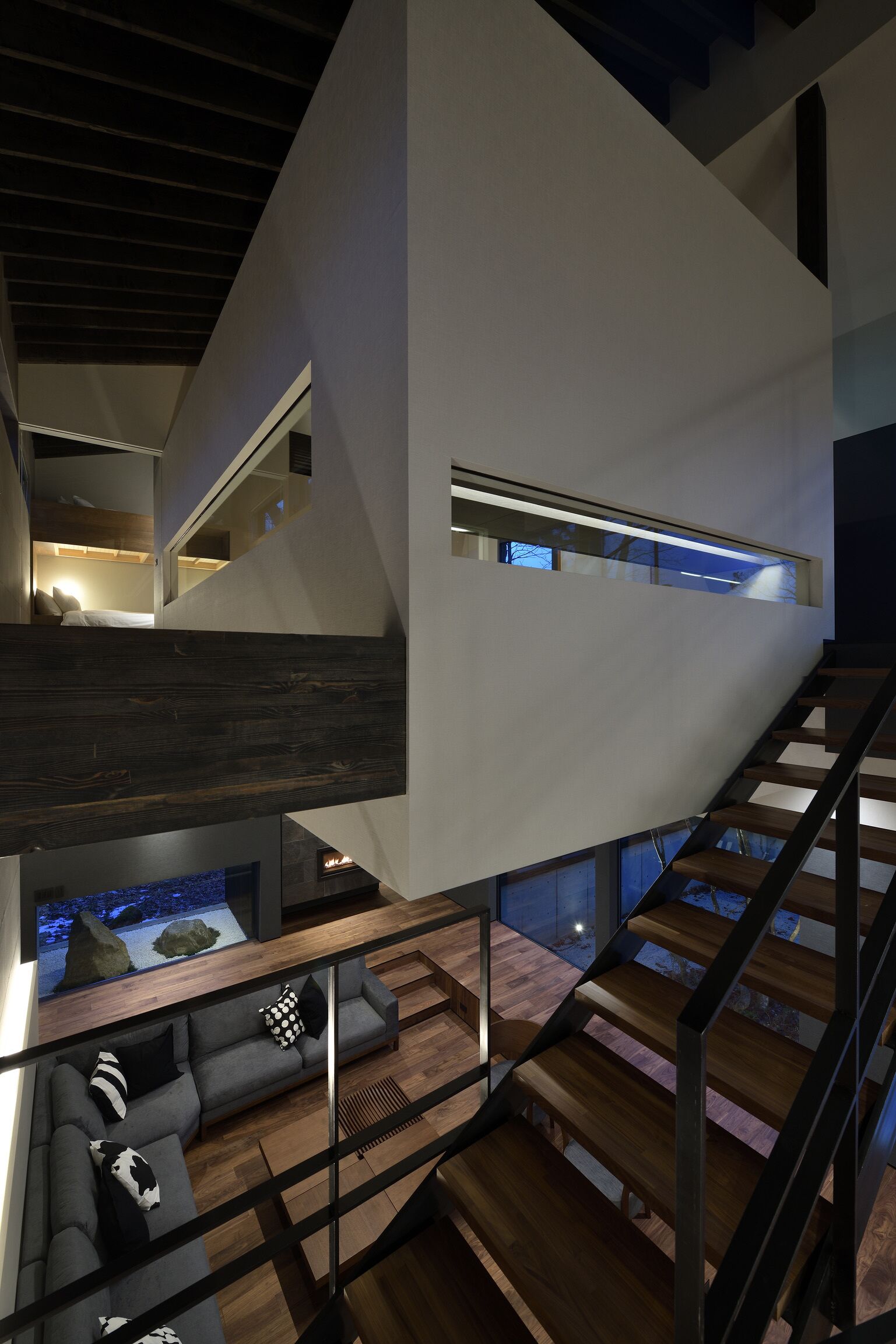 A modern interior with a staircase, a sofa, and a view of the outside.