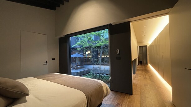 Ein modernes Schlafzimmer mit Bett, einer Schiebetür zum Balkon und Holzboden.