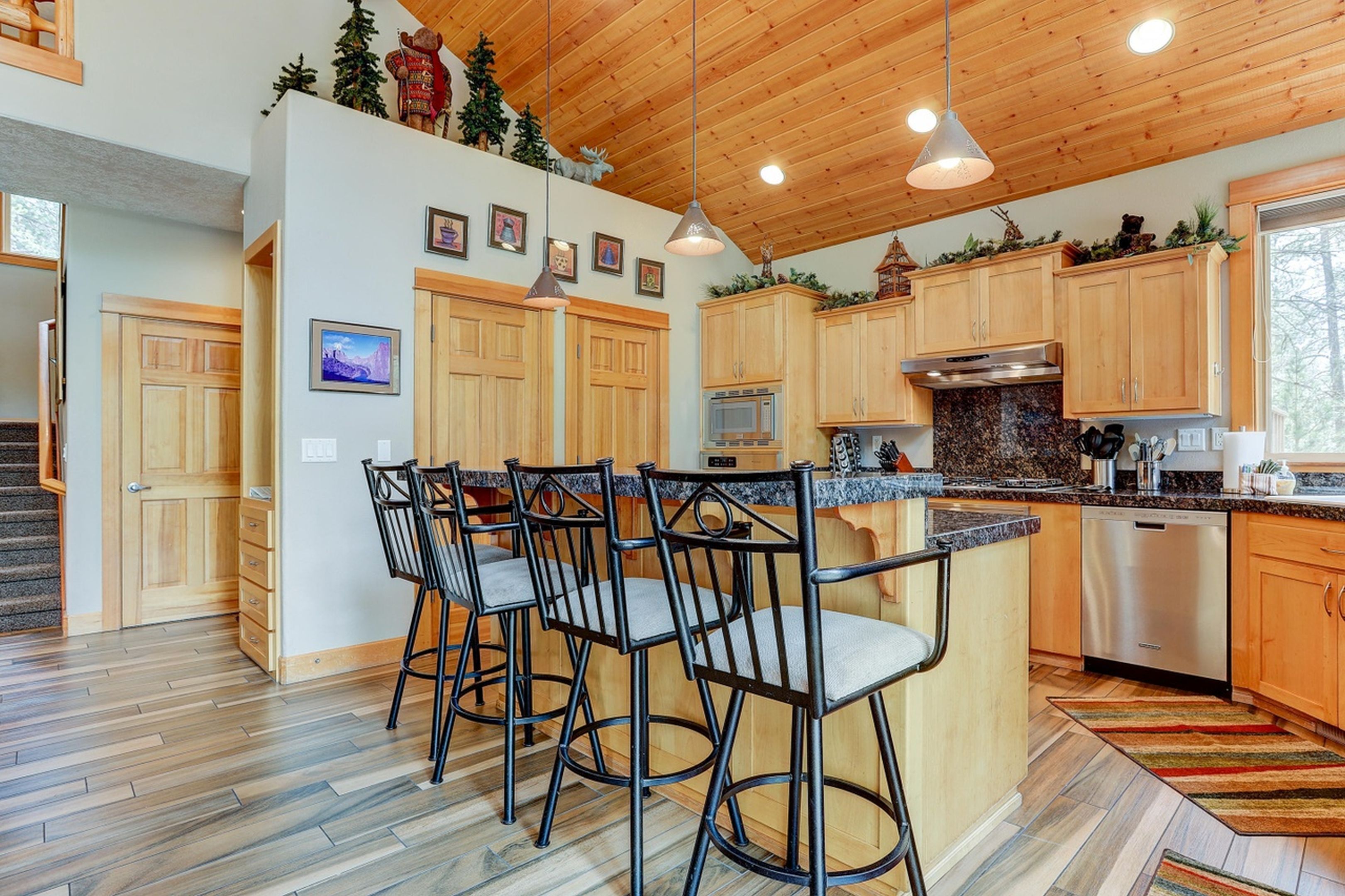 A modern kitchen with wooden cabinets, a granite countertop, and a central island with bar stools.