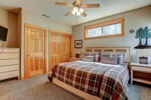A bedroom with a bed, wooden wardrobe, ceiling fan, window, and a small decorative tree on the wall. - 5BR+Bunk,5.5BA,4 King,Near SHARC Pool,Hot tub,WiFi,A/C,Bikes,EV Chrg (Sunriver)