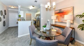 Relax in this stylish living area with a glass-top dining table and comfortable seating for two.