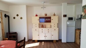 Una cocina compacta con un refrigerador blanco, un microondas y un taburete de madera.