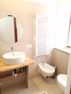 Ein Badezimmer mit einem runden Waschbecken, einem Bidet und einer Toilette.