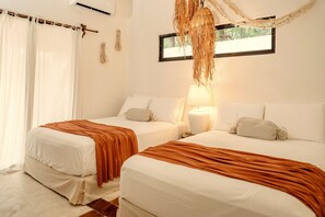Een hotelkamer met twee bedden, een raam en een hanglamp.