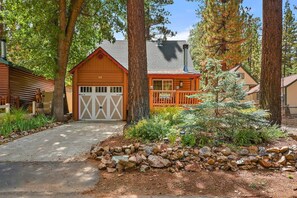 A cabin with a garage, surrounded by trees and a rock garden. - Nestled in Moonridge Close to Both Resorts, Hiking & Biking Trails! (Big Bear Lake)