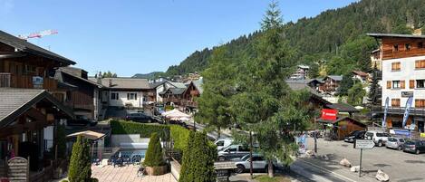 A town square with traditional wooden buildings, a tennis court, and a mountain backdrop.