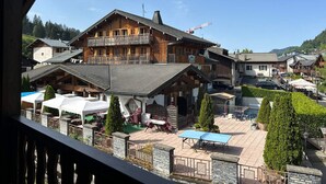 Un chalet de madera con balcón, mobiliario exterior y vistas del pueblo circundante.
