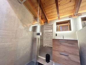Ein kleines Badezimmer mit Holzbalkendecke, einem Spiegel, einem Waschbecken und einem Handtuchhalter.
