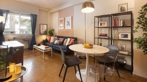 Uma sala de estar moderna com um sofá, mesa de centro e mesa de jantar. Há estantes e um vaso com planta.
