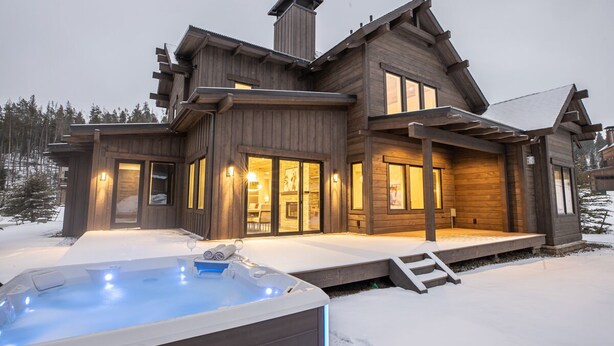 A large wooden cabin with a hot tub in the snow.