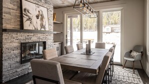 A modern dining area with a brick wall, a fireplace, and a large table with chairs.