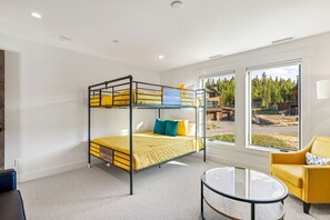 A bunk bed room with a glass table and a yellow armchair.