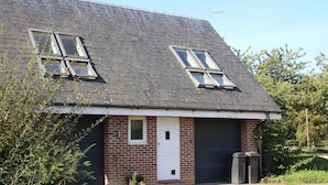 Une maison à deux étages avec un toit en pente, deux lucarnes, un garage et une porte blanche.