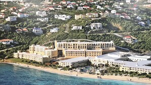 Un hotel costero con varias edificaciones, una playa y vistas al mar.
