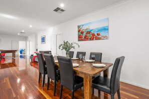 A dining area with a wooden table, black chairs, and a painting on the wall.