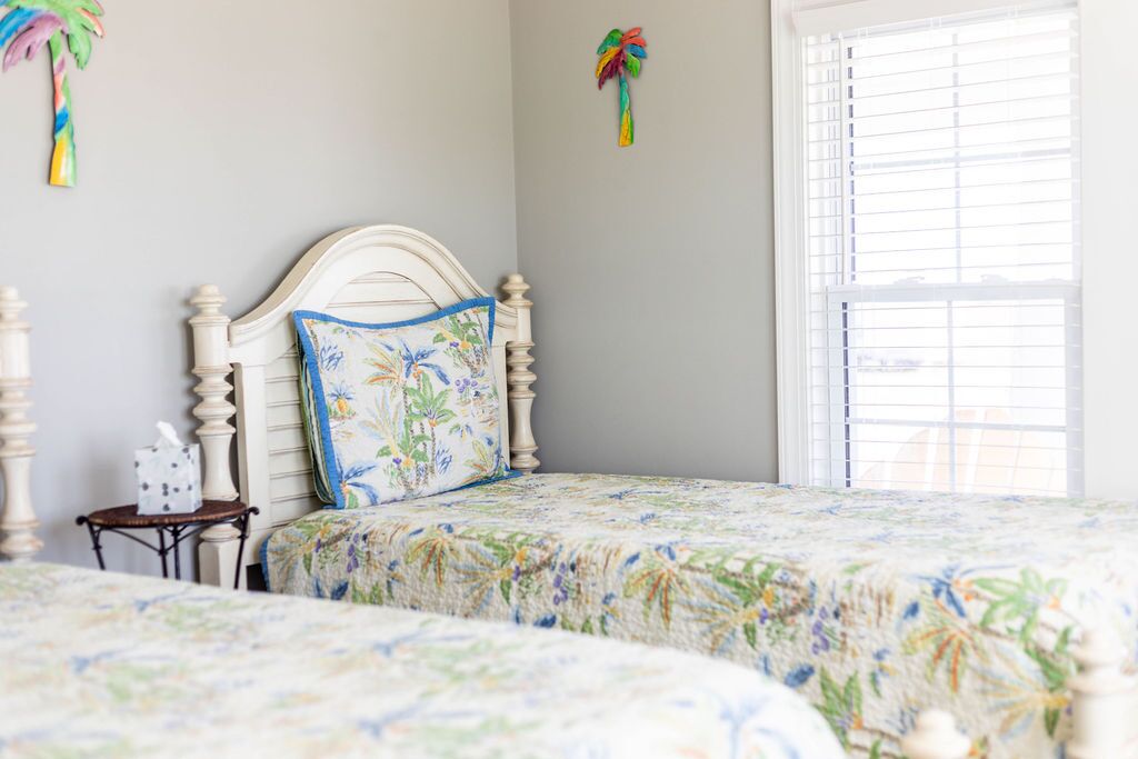 A bedroom with a bed featuring a floral bedspread, a wooden headboard, and a small bedside table with a tissue box.