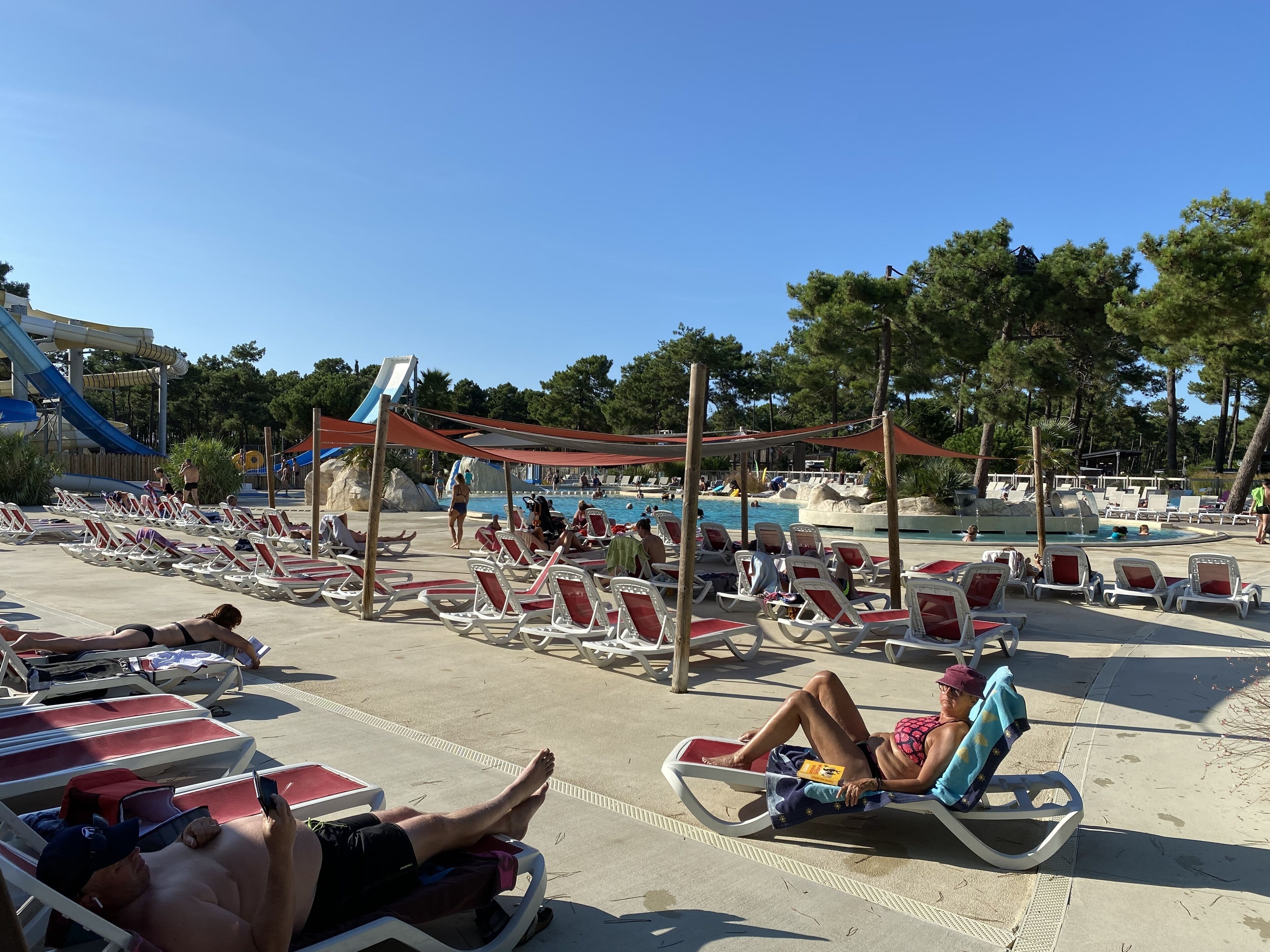 A poolside area with sun loungers, a water slide, and a pool.