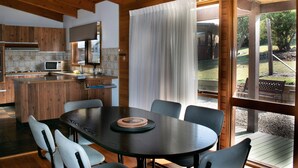Une cuisine moderne avec des meubles en bois, un four à micro-ondes encastré et un coin repas comprenant une table ronde et des chaises.