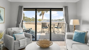 A modern living room with a balcony, grey sofas, a table, and a lamp. - Bay Views, Marina, and Golf Course ~ Golf Cart (Miramar Beach)