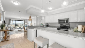 A modern kitchen with white cabinets, a granite countertop, and stainless steel appliances. - Bay Views, Marina, and Golf Course ~ Golf Cart (Miramar Beach)