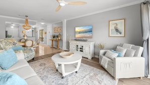 A living room with a white sofa, a round coffee table, a white cabinet, and a ceiling fan. - Bay Views, Marina, and Golf Course ~ Golf Cart (Miramar Beach)