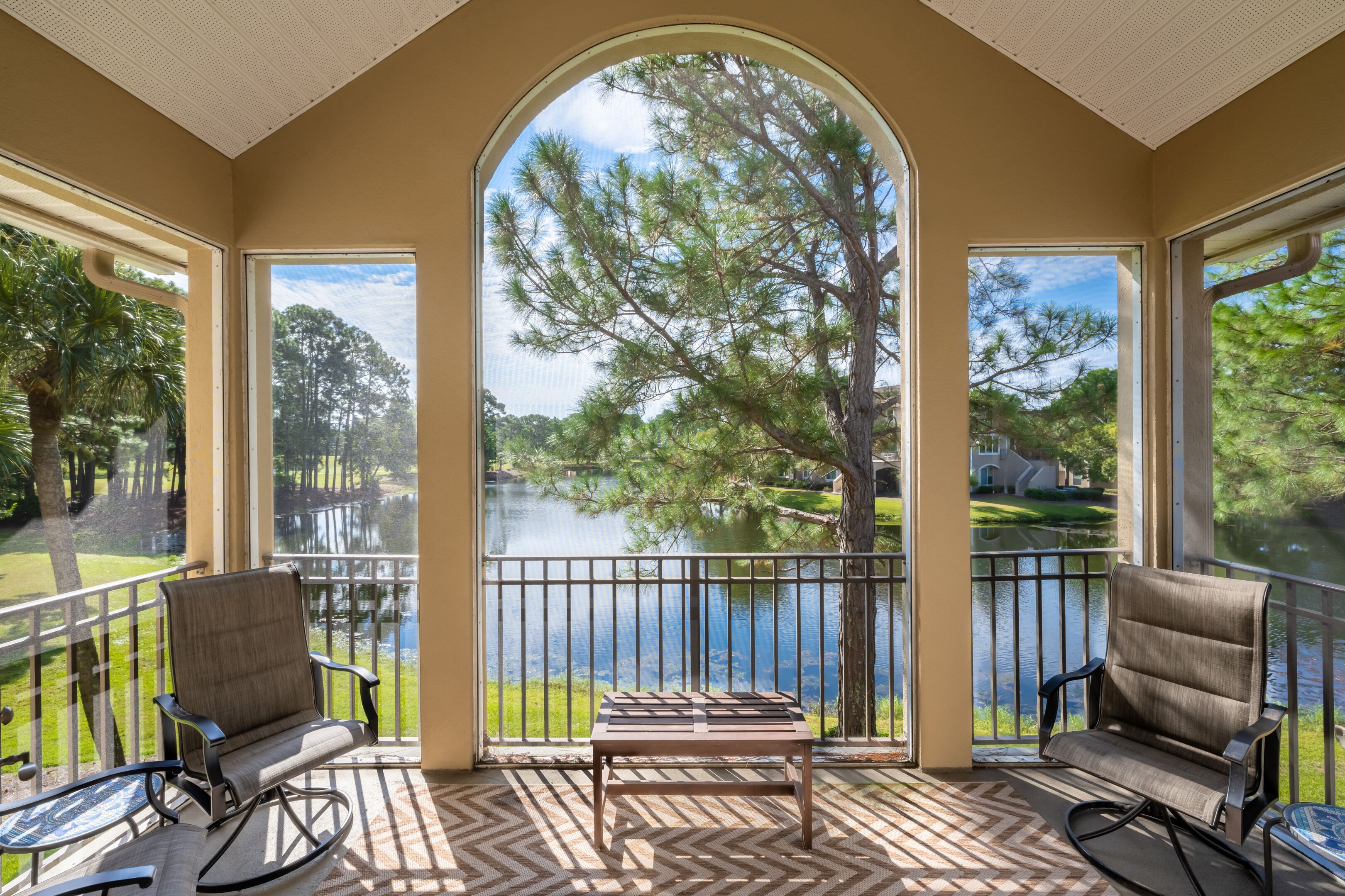 A sunroom with a view of a lake, two rocking chairs, and a small table.