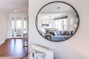 Uma sala de estar moderna com um espelho redondo, um sofá e um espaço de jantar com mesa e cadeiras.