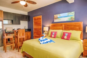 A hotel room with a bed, a desk, and a kitchenette.