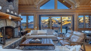 A spacious living room with a fireplace, large windows offering mountain views, and a cozy seating area. - Amazing Days Lodge - 6 Bdrms, Ski-In-Ski-Out, Epic Views, Hot Tub, Firepit! (Mountain Village)