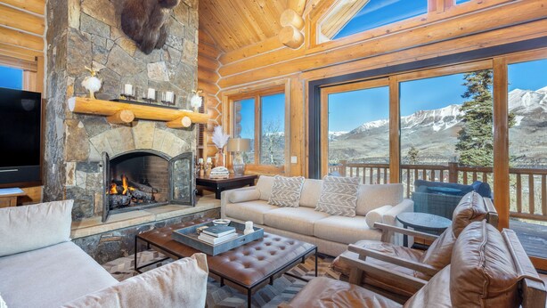 A log cabin interior with a stone fireplace, a sofa, a coffee table, and a television. - Amazing Days Lodge - 6 Bdrms, Ski-In-Ski-Out, Epic Views, Hot Tub, Firepit! (Mountain Village)