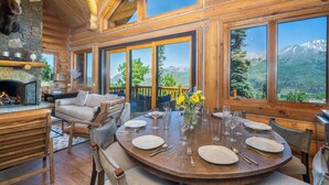 A wooden cabin with a fireplace, dining area, and large windows offering mountain views. - Amazing Days Lodge - 6 Bdrms, Ski-In-Ski-Out, Epic Views, Hot Tub, Firepit! (Mountain Village)