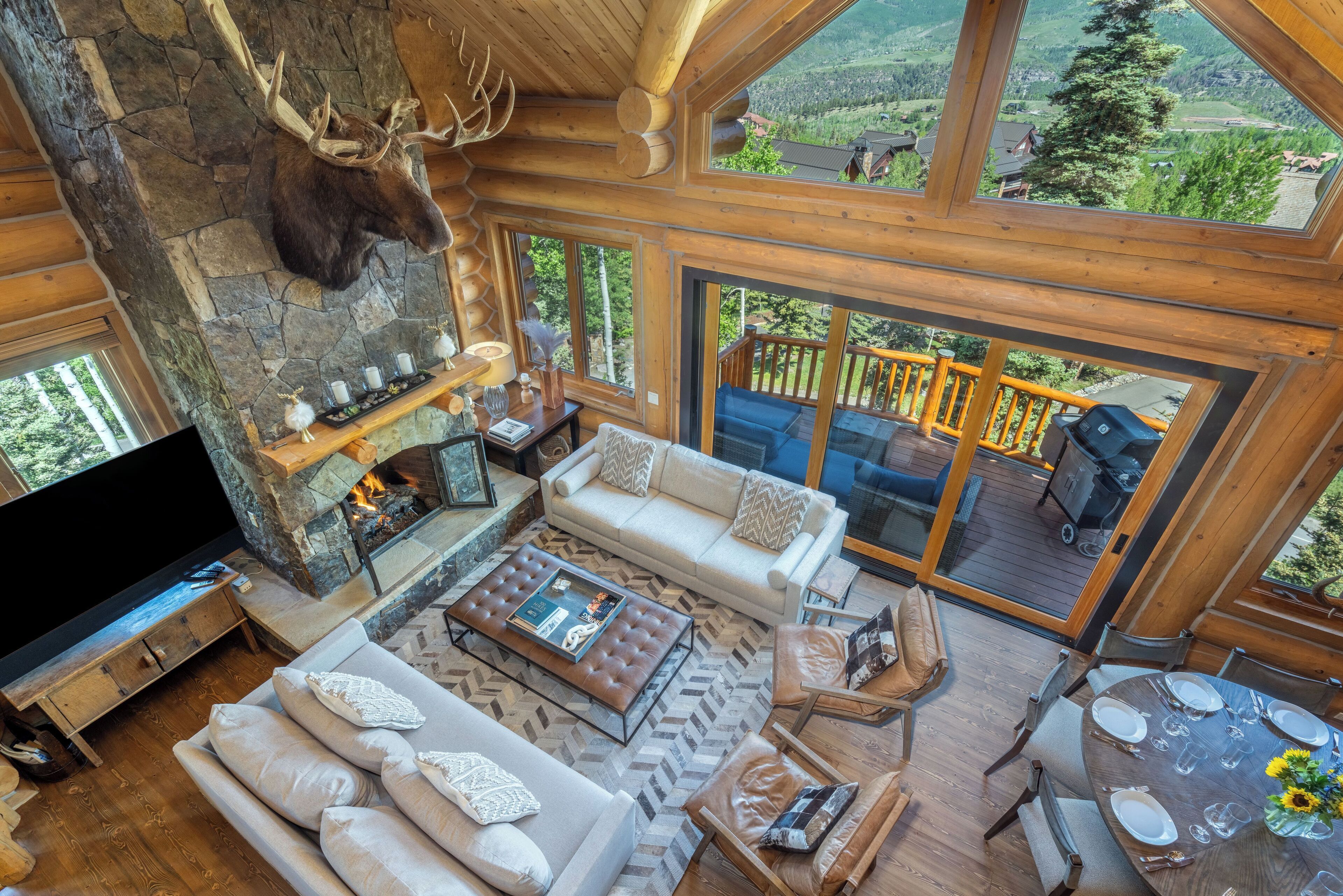 Amplia sala de estar con chimenea de piedra, muebles de madera y un televisor grande.