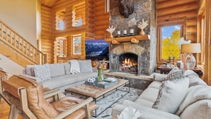 A log cabin interior with a stone fireplace, leather furniture, and a television. - Amazing Days Lodge - 6 Bdrms, Ski-In-Ski-Out, Epic Views, Hot Tub, Firepit! (Mountain Village)