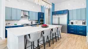 Een moderne keuken met blauwe kastjes, een wit eiland en een roestvrijstalen koelkast.