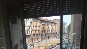 Quarto com uma grande janela com vista para a rua da cidade.