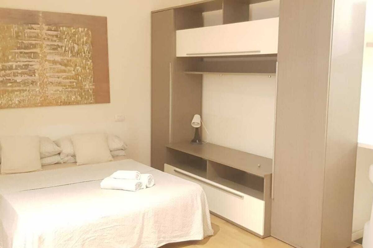 A bedroom with a bed, a wardrobe, a desk, and a chair.