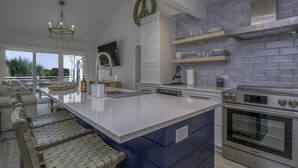 A modern kitchen with a large island, stainless steel appliances, and a view to the outdoors.