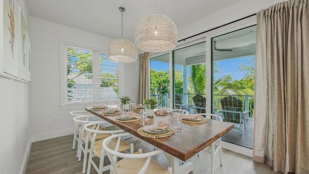 A dining area with a wooden table set for six, white chairs, and two hanging wicker chandeliers. - Private Home with Custom Pool and Spa! (Bradenton Beach)