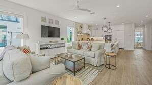 A spacious living area with a sofa, coffee table, and a TV. There is a kitchen area with a dining set and a ceiling fan. - Private Home with Custom Pool and Spa! (Bradenton Beach)