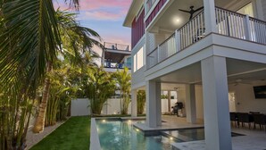 A two-story house with a swimming pool, outdoor furniture, and a balcony. - Private Home with Custom Pool and Spa! (Bradenton Beach)