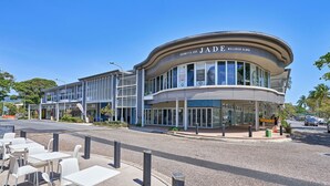 A modern building with a curved facade, featuring a wellness clinic named 'Jade Wellness Clinic'. - Costa Royale 3 Bedroom Beachfront Apartment (Trinity Beach)