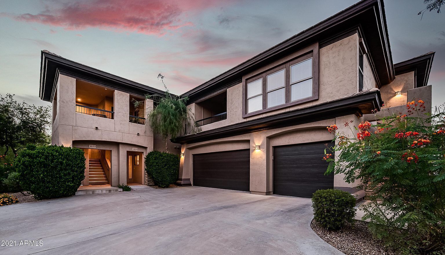 A modern two-story house with a garage, a covered driveway, and a landscaped garden.