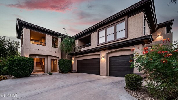 A modern two-story house with a garage, a covered driveway, and a landscaped garden.