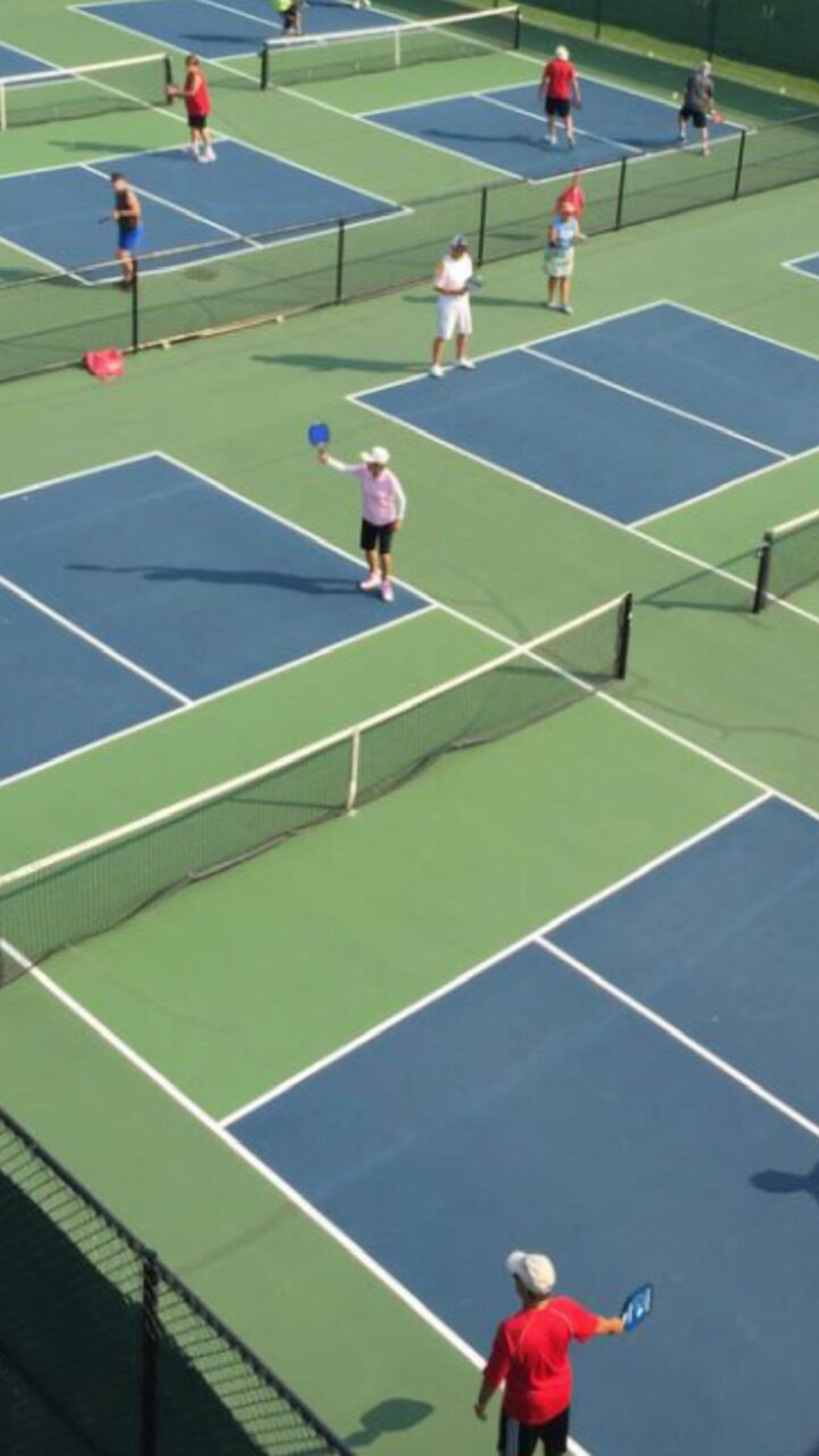 Un court de tennis avec plusieurs joueurs et un filet.