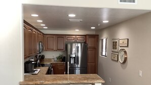 Cocina moderna con armarios de madera, electrodomésticos de acero inoxidable y encimera de granito.