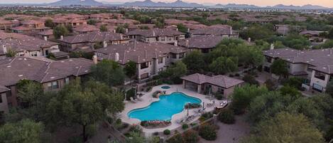 A residential area with a swimming pool surrounded by houses and greenery.