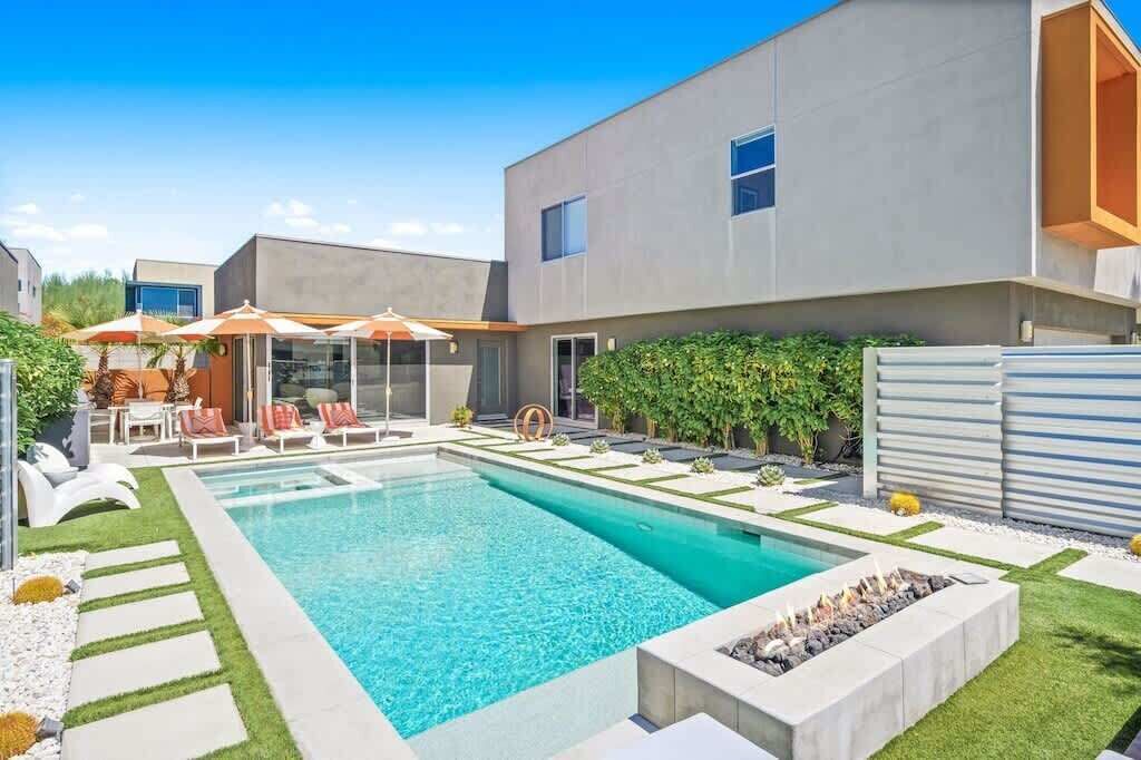 Une maison moderne dotée d’une piscine, d’un espace salon extérieur et d’un foyer.