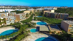 Un complexe hôtelier doté de plusieurs piscines, de palmiers et offrant une vue sur l’océan.