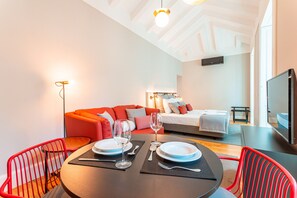 A modern hotel room with a dining area, a bed, and a TV.